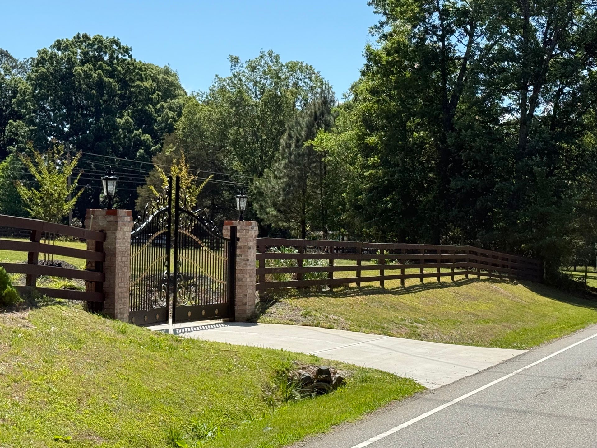 Fence Staining — split-rail fence with iron gate and brick pillars, fresh dark brown stain in Durham, NC