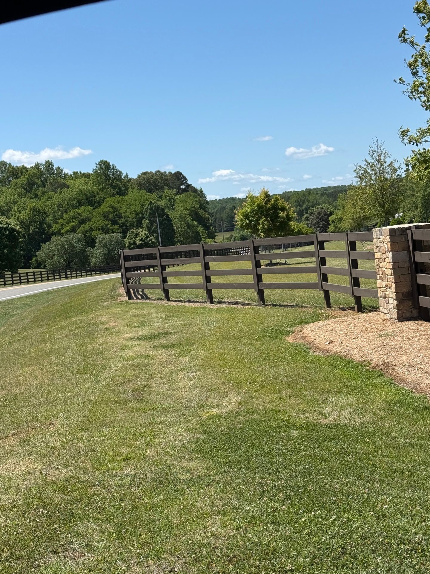 Fence Staining — dark-stained multi-rail fence in open grassy area in Hillsborough, NC
