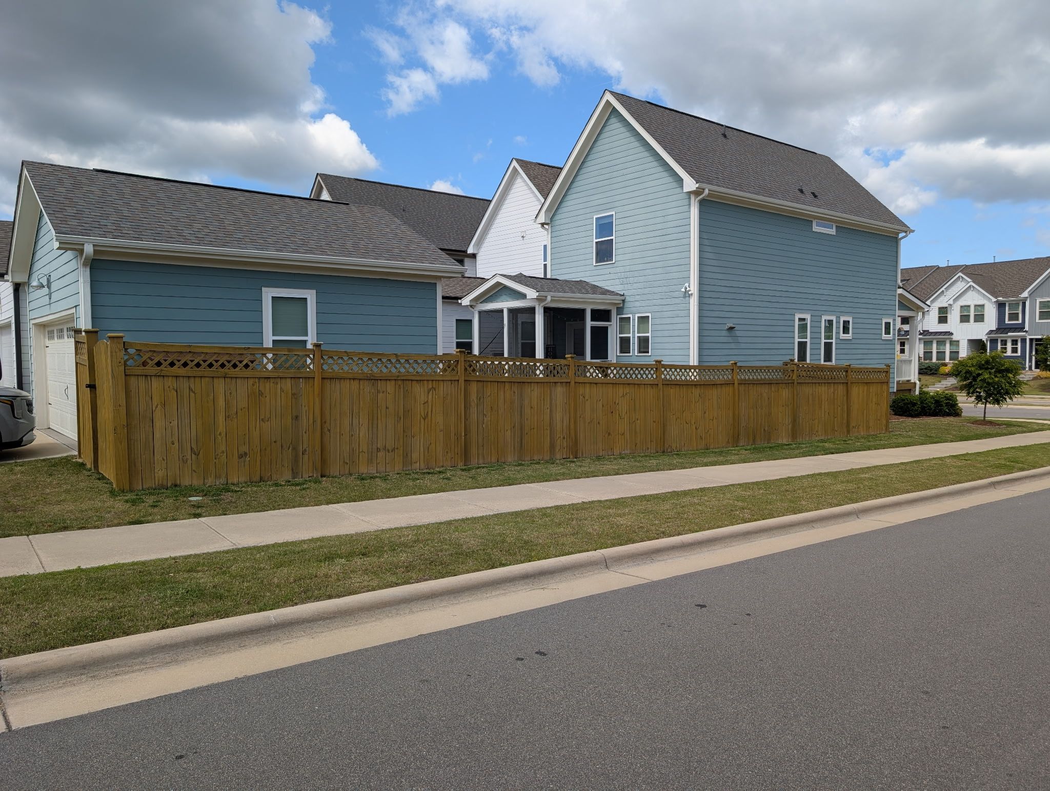Fence Staining — wood privacy fence freshly stained in honey-tan along a residential street in Apex, NC