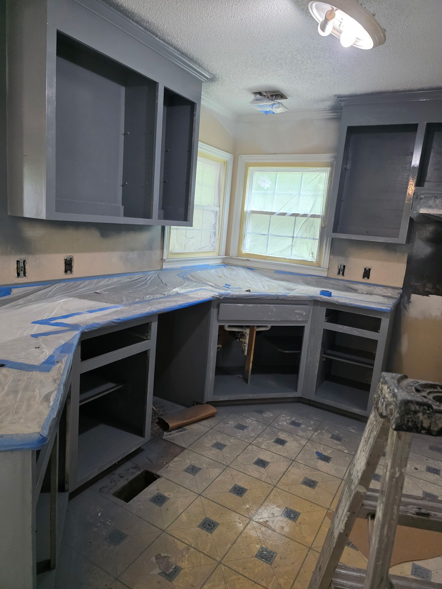 Interior Painting — kitchen with blue-gray cabinet refresh and countertops masked for spray in Apex, NC